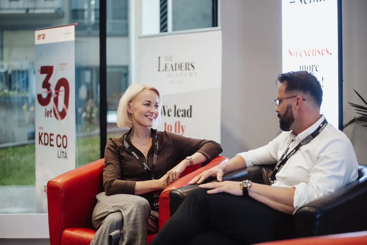 Rozhovor dvou účastníků na pohovce u bannerů partnerů, Trendy Leaders
